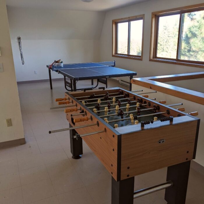 A foosball table and a table tennis table in the upstairs common area of the Bozett Barn.