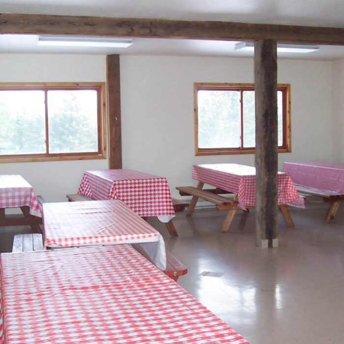 Picnic tables covered with red and white tablecloths are seen inside the Bozett Barn at Lael.