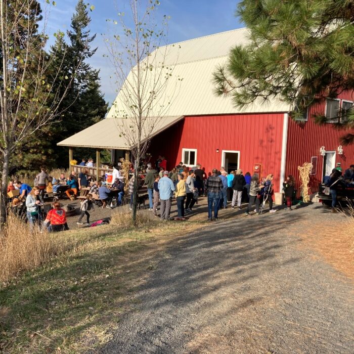 A crowd of people in front of the Bozett Barn at Lael on a sunny day.
