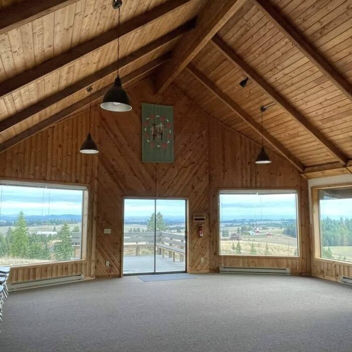 Interior of a wooden chapel. Large windows give an expansive view of the Palouse.