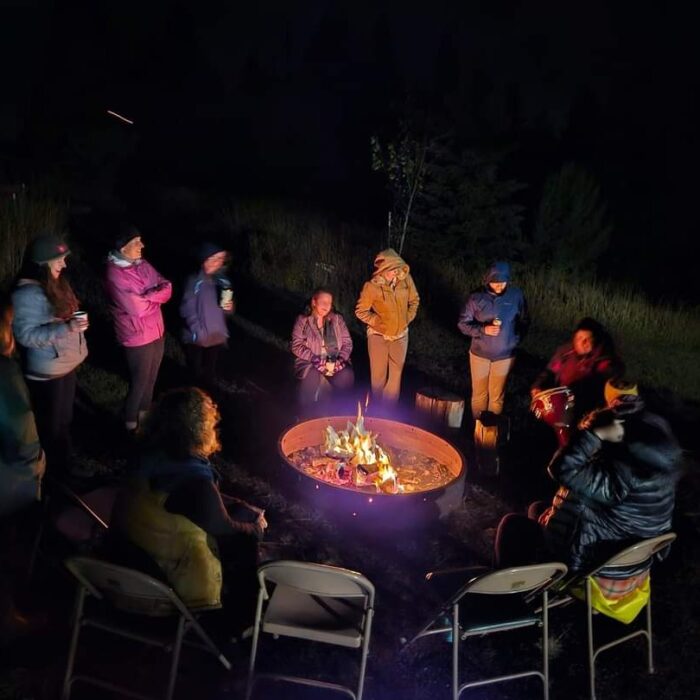 People gather around an outdoor fire pit at night at Lael.